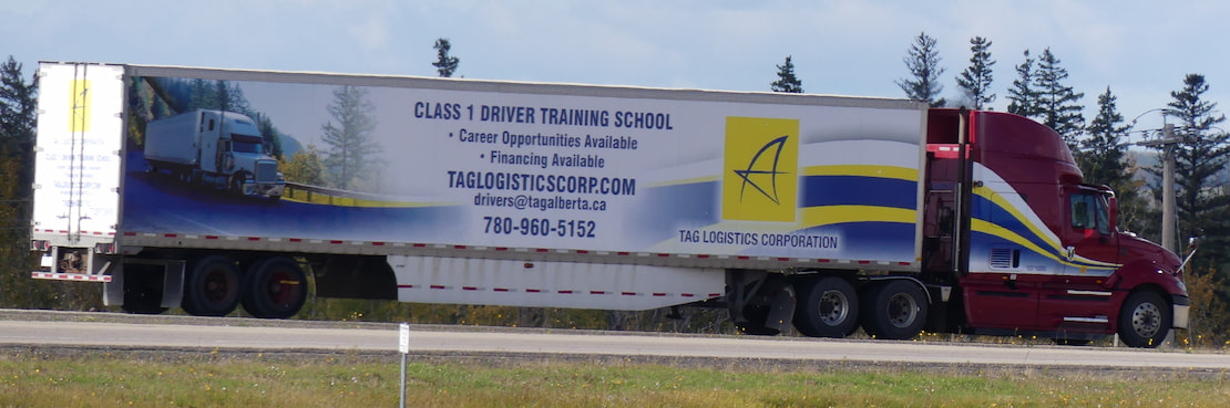 a red semi-truck with a trailer that says Tag Logistics Corporation and Class 1 Driver Training School