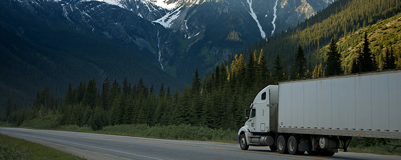 white semi-truck on the road and on the foot of a snowy mountain